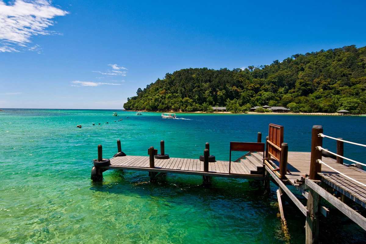 Lang Co Beach Hue scenic wooden pier and turquoise water view Lang Co Beach Hue features a wooden pier over turquoise water with lush hills and boats, showcasing the natural coastal beauty between Hue and Da Nang.
