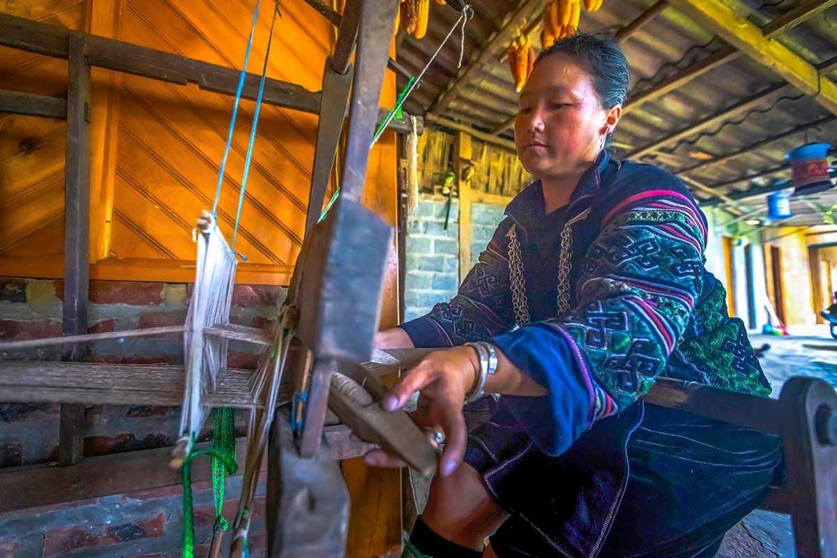 Lao Chai Village Sapa traditional Hmong weaving crafts Lao Chai Village Sapa Hmong artisan weaving with traditional loom in colorful, rustic wooden house