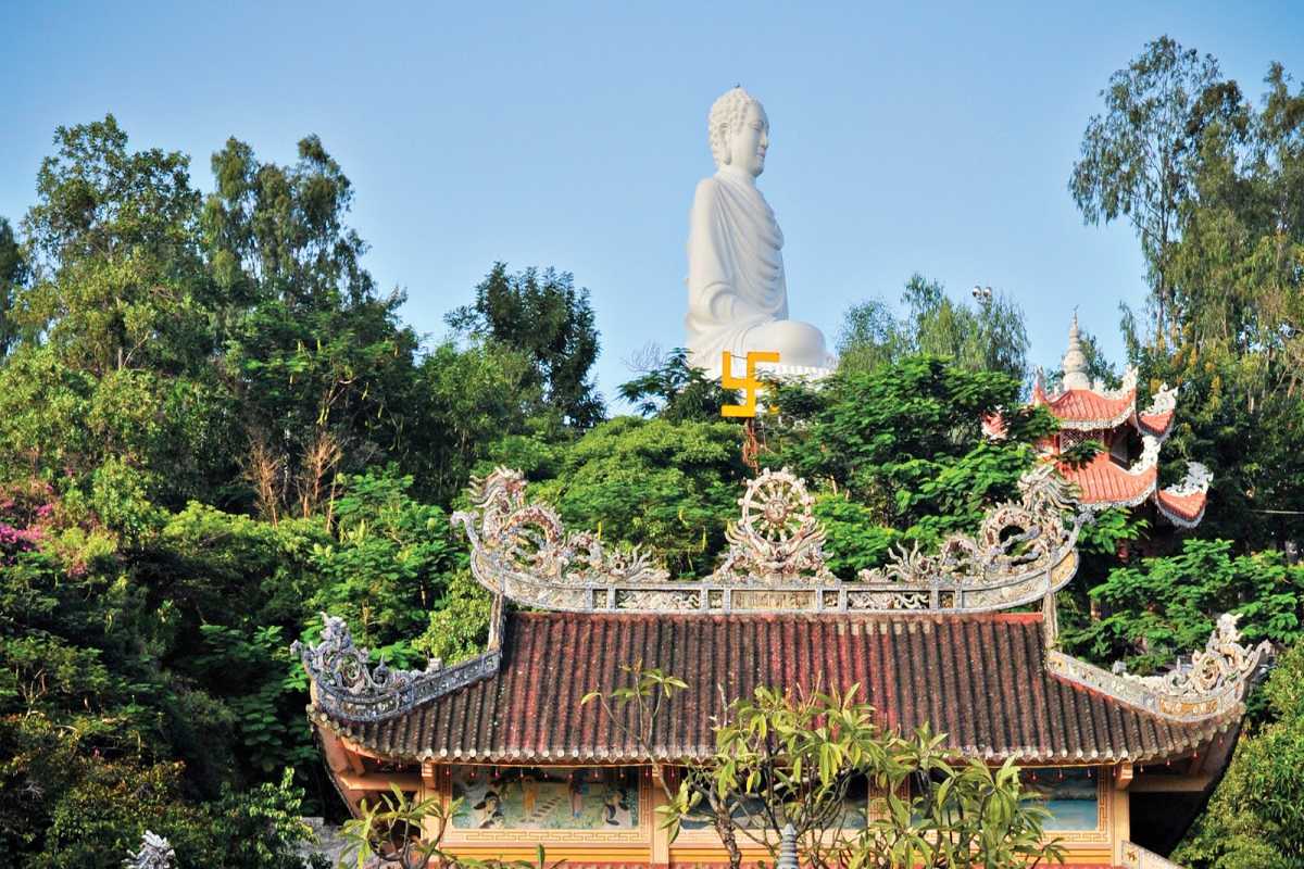 The large white Buddha statue at Long Son Pagoda rises above green trees in Nha Trang, Vietnam.