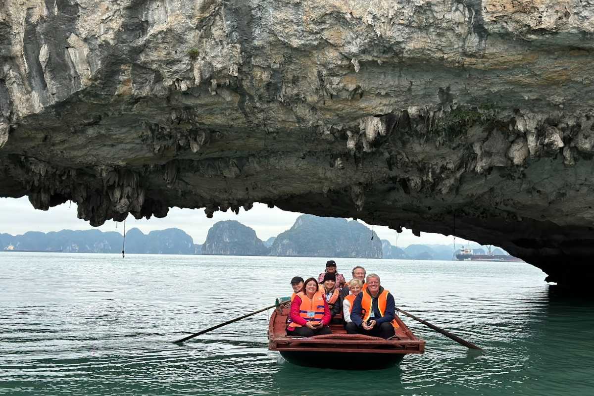 Luon Cave Halong Bay Limestone Arch and Kayaking Visitors Kayakers and boats near limestone archway of Luon Cave with green cliffs and calm water