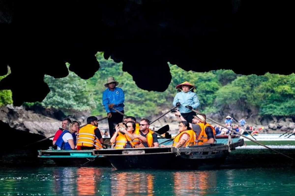 Luon Cave Halong Bay Scenic Boat Entrance Tourists on boat entering Luon Cave in Halong Bay surrounded by limestone cliffs and green water