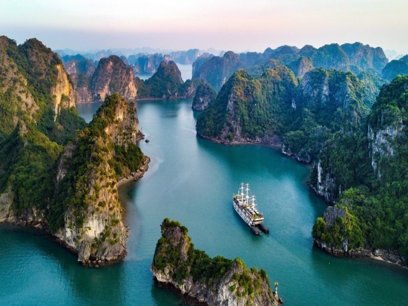 Luxury cruise sailing through Cong Dam Fishing Village, Bai Tu Long Bay, with limestone cliffs and calm waters.