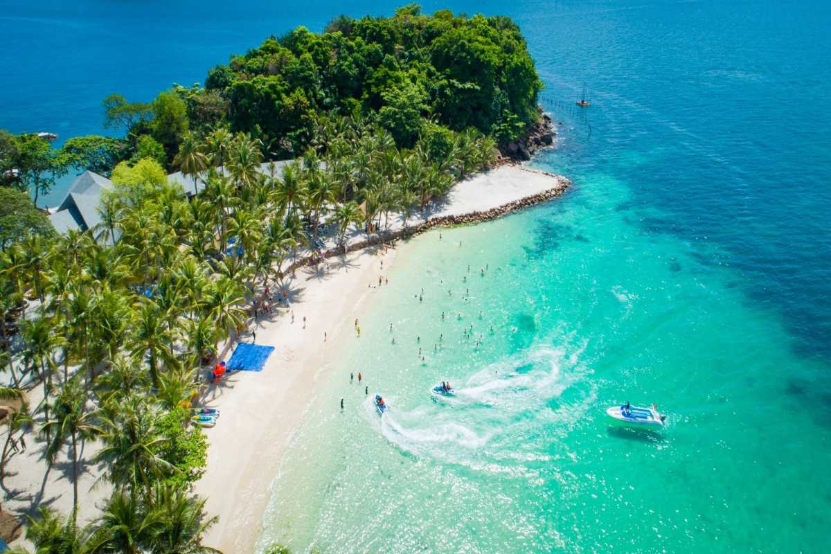 White sandy beach and turquoise water at May Rut Trong Island in Phu Quoc with palm trees lining