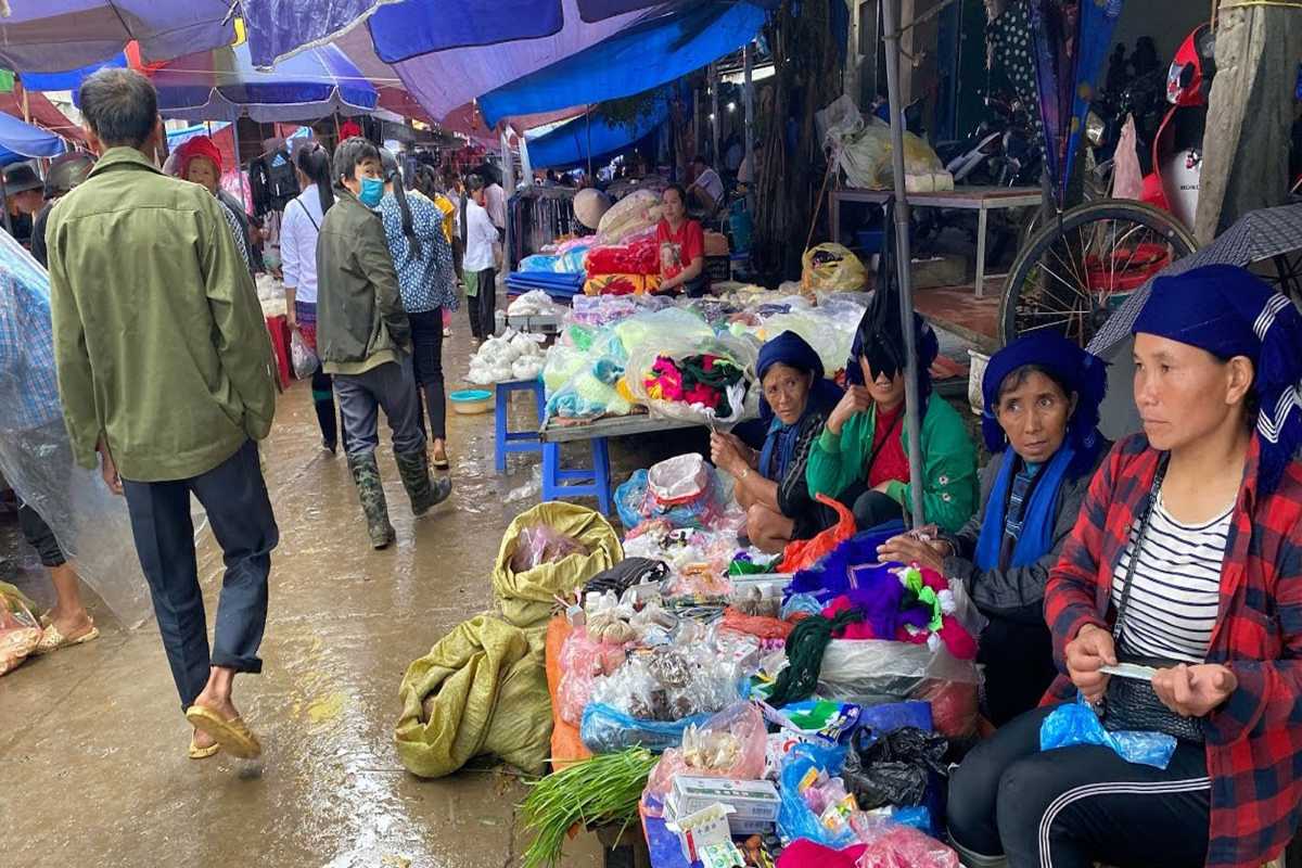 Muong Hum Market Sapa fresh produce and traditional costumes Muong Hum Market Sapa with ethnic minorities trading fresh produce, wearing vibrant traditional costumes.