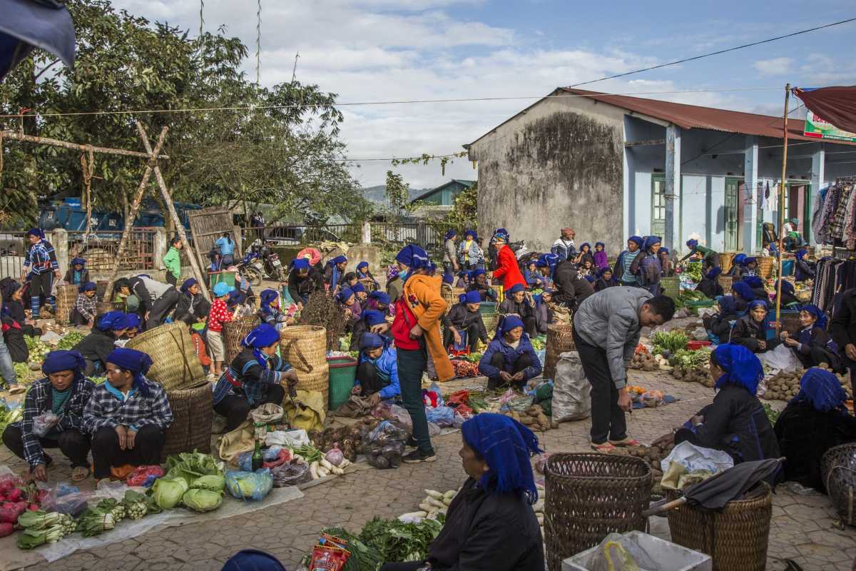 Muong Hum Market Sapa morning vegetable market outdoors Muong Hum Market Sapa offers a lively outdoor vegetable market with ethnic women selling fresh produce in blue scarves.