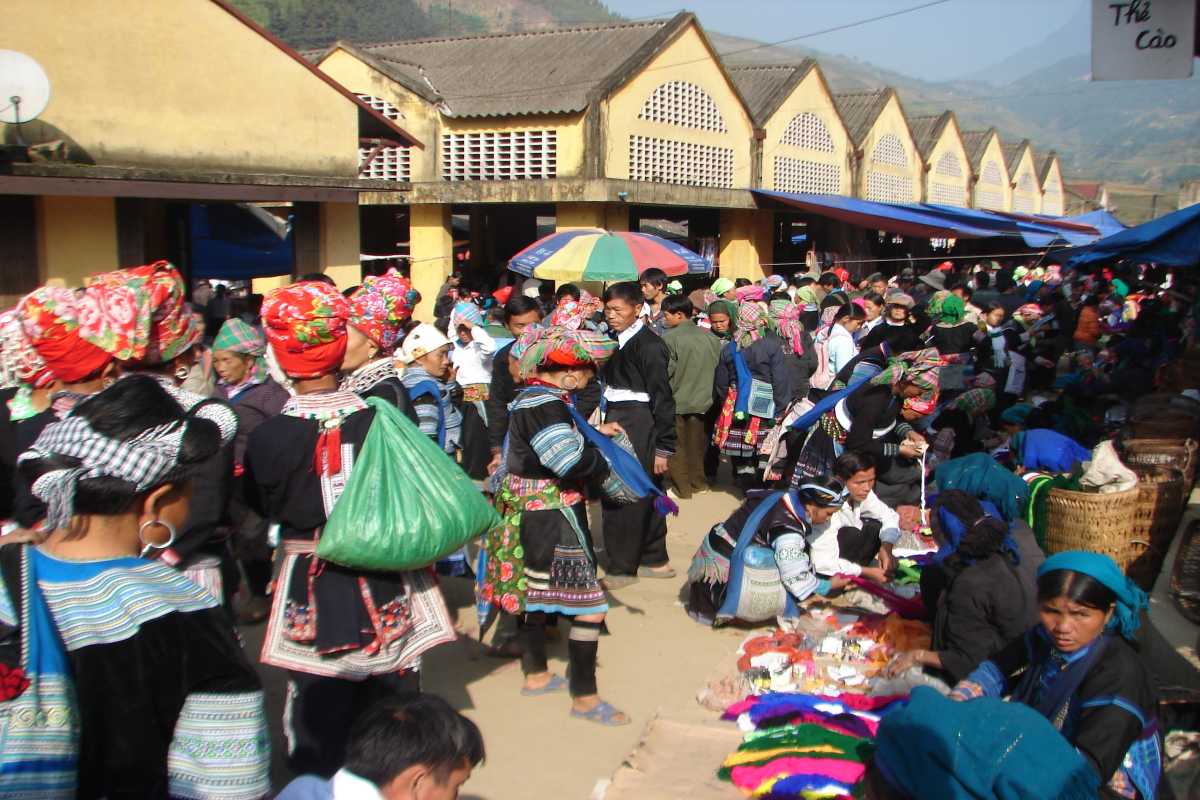 Muong Hum Market Sapa traditional dress Sunday gathering Muong Hum Market Sapa on Sunday with ethnic groups in traditional dress, colorful headscarves, and busy crowds.