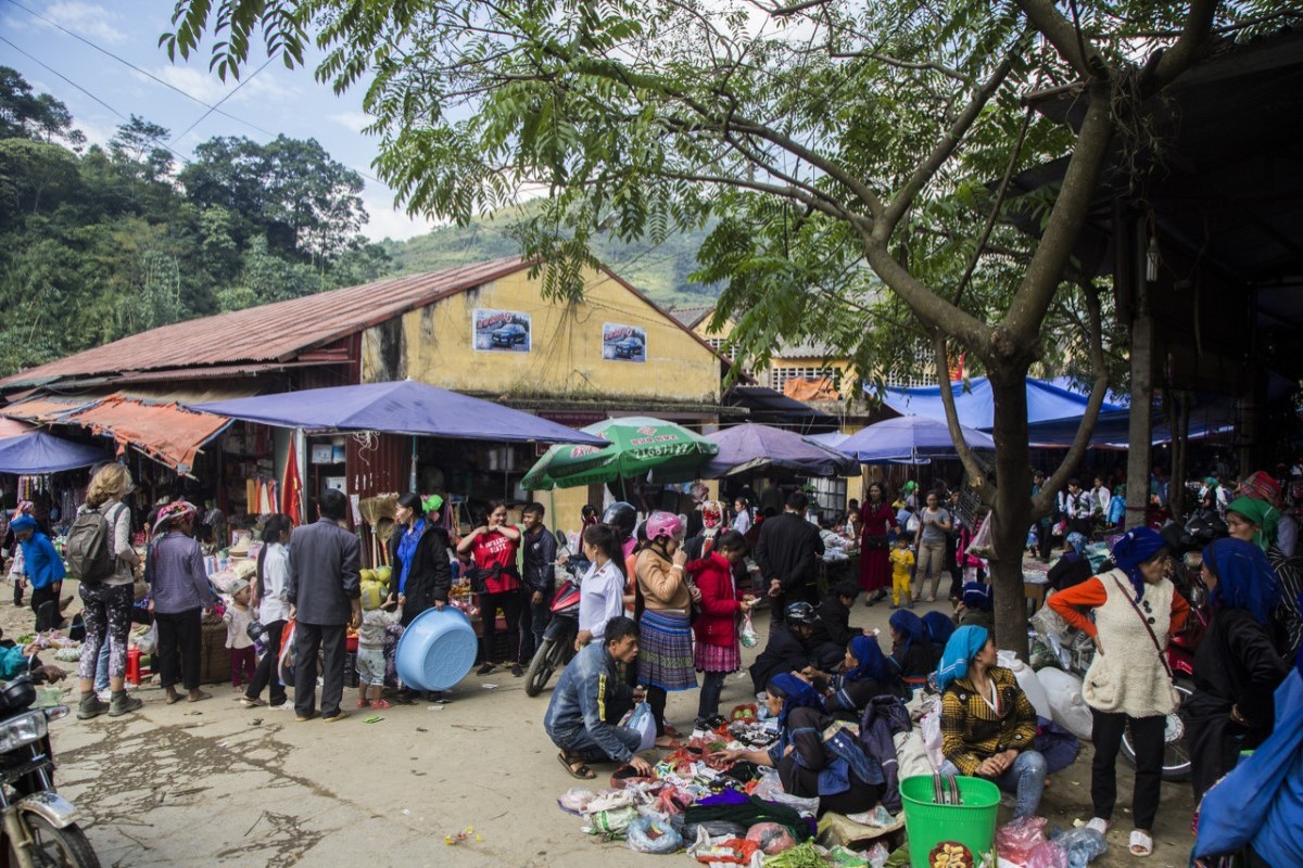 Crowded scene at Muong Hum Market with local vendors and visitors.