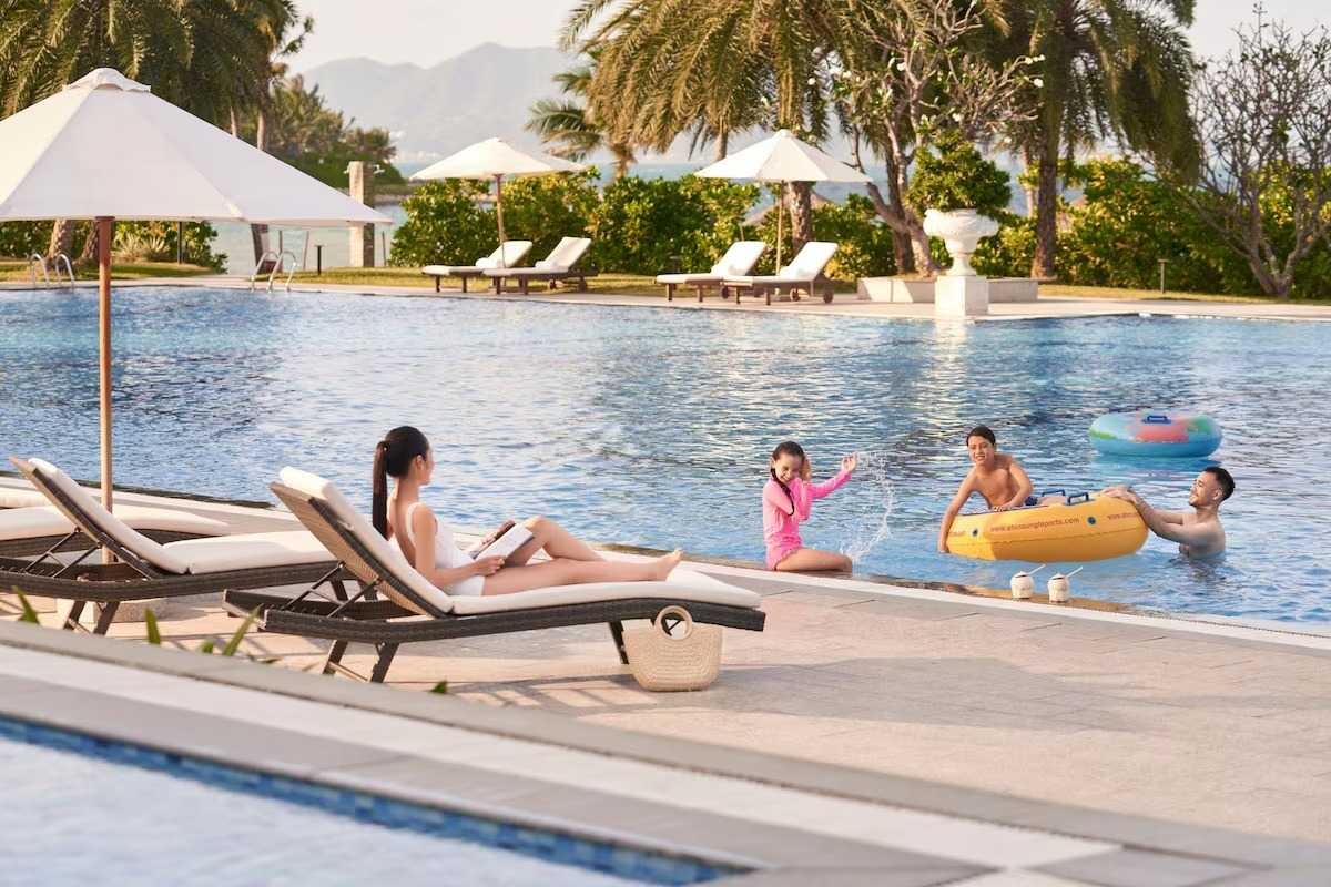 Family relaxing by the pool in Nha Trang Bay with palm trees and mountain views