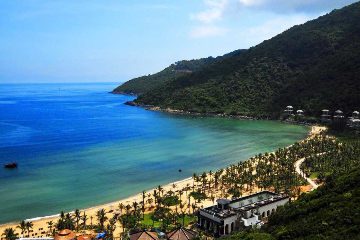 Non Nuoc Beach Da Nang sweeping bay and lush green hills Non Nuoc Beach Da Nang sweeping bay is surrounded by lush hills, clear blue sea, and palm trees along the coast.