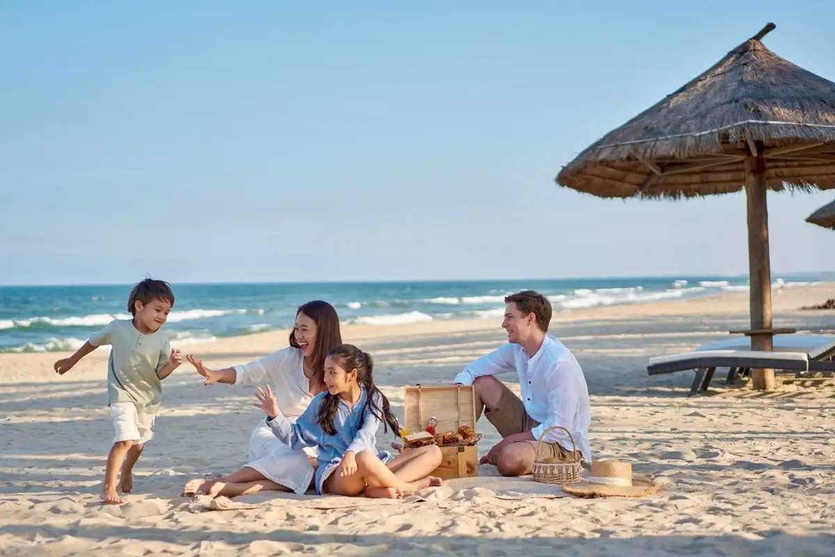 Non Nuoc Beach Da Nang family picnic on sandy beach Non Nuoc Beach Da Nang family enjoys a joyful picnic and playtime on the clean sandy shore under beach huts.