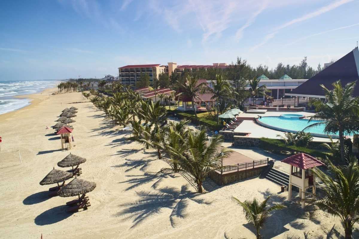 Non Nuoc Beach Da Nang oceanfront resort with palm-lined pool Non Nuoc Beach Da Nang resort features a large pool, sun loungers, and direct access to the sandy beach, lined with swaying palm trees.