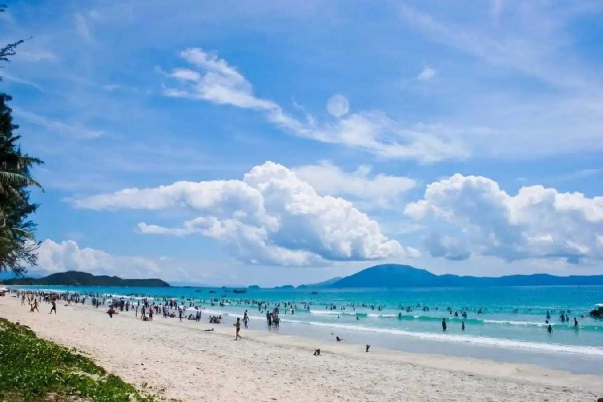 Non Nuoc Beach Da Nang vibrant beach life and turquoise sea Non Nuoc Beach Da Nang bustles with visitors enjoying white sand, gentle waves, and clear turquoise water under a bright blue sky.