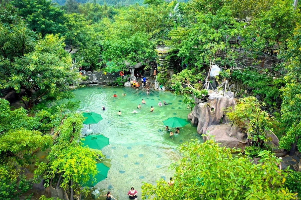 Visitors enjoying a natural pool surrounded by lush greenery at Nui Than Tai Hot Springs Park in Da Nang, Vietnam