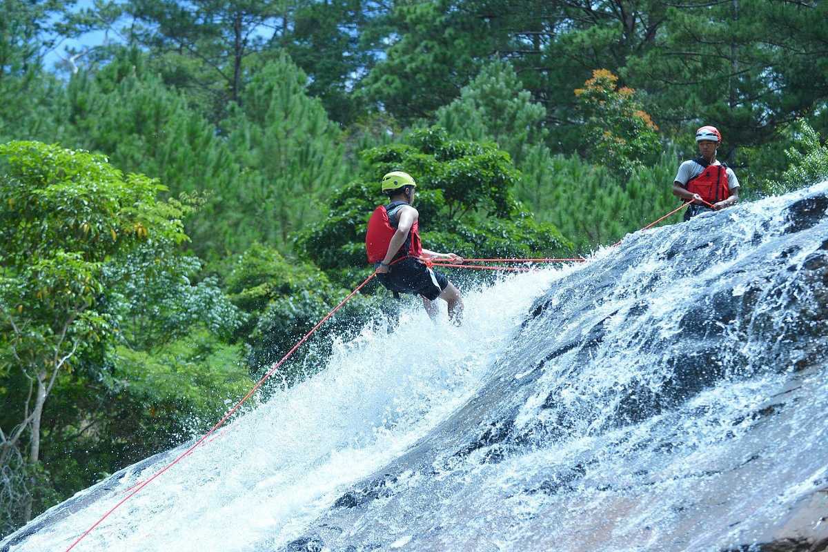 Outdoor Canyoning Experience at Datanla Waterfalls Two adventurers rappelling down the rocky streams of Datanla Waterfalls amid vibrant forest surroundings