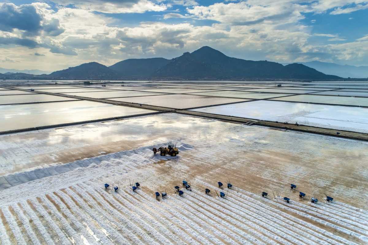 Panoramic View of Dam Vua Salt Ponds and Mountains Wide aerial view of salt ponds reflecting the sky and nearby mountains at Dam Vua Salt Fields