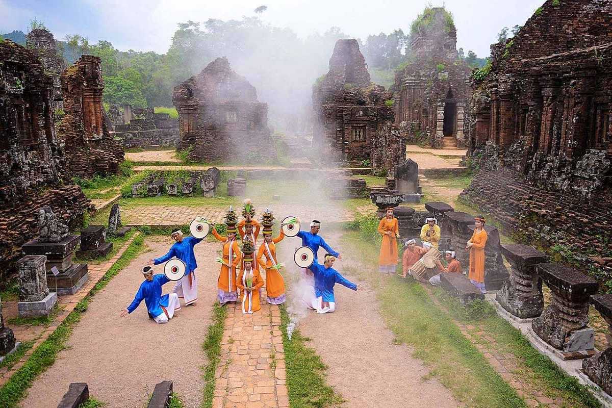 Panoramic View of My Son Sanctuary Ruins Wide panoramic scene of My Son Sanctuary’s scattered temple ruins with visitors and forest in the background