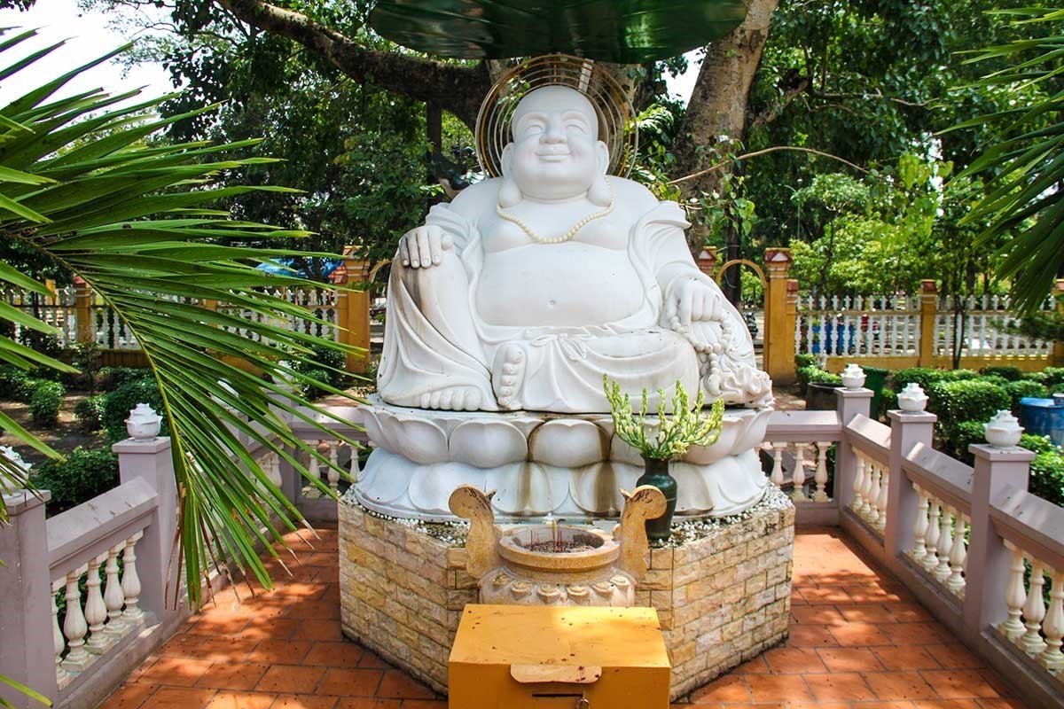 Laughing Buddha statue surrounded by greenery at Giac Lam Pagoda in Ho Chi Minh City