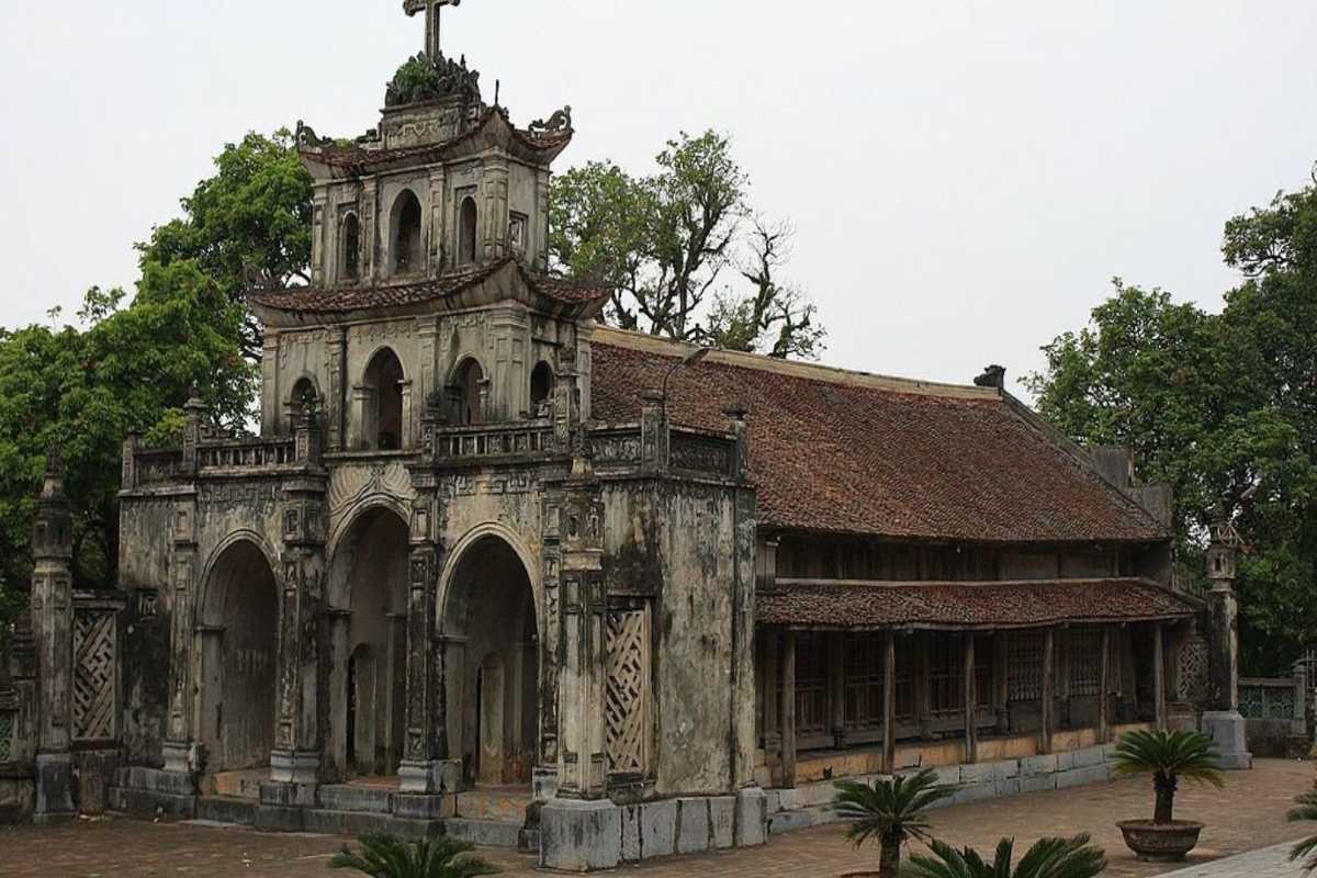 Phat Diem Cathedral Ninh Binh historic chapel front Phat Diem Cathedral Ninh Binh front view of chapel with cross, stone arches, and mature trees