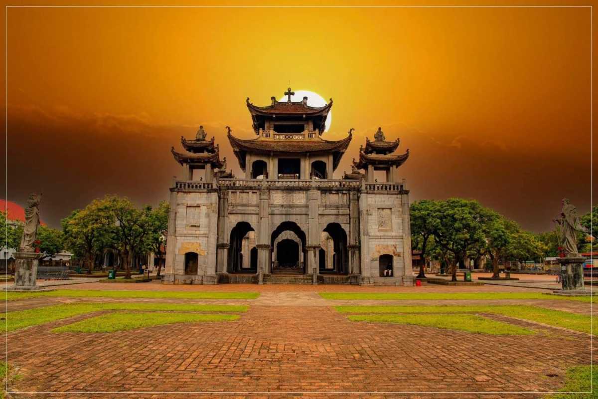 Phat Diem Cathedral Ninh Binh entrance at sunset Phat Diem Cathedral Ninh Binh entrance gate highlighted by golden sunset and pagoda roofs