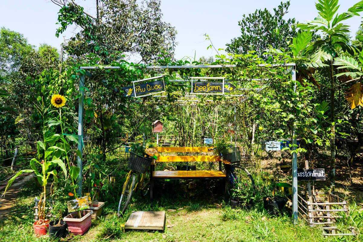 Beehive area with protective barrier at Phu Quoc Bee Farm Designated honeybee work zone with warning sign and multiple beehives at Phu Quoc Bee Farm