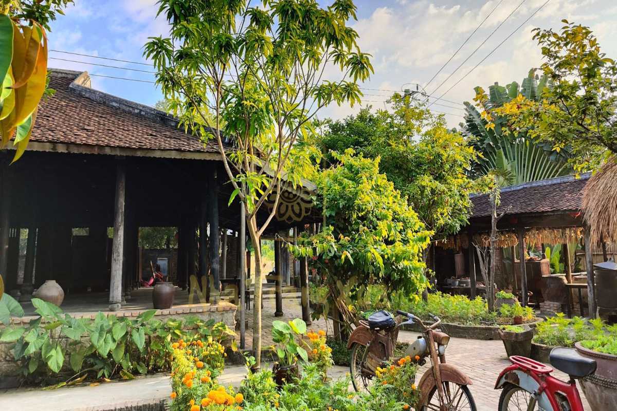 Traditional courtyard at Phu Vinh Ancient Village with tiled roof, clay pots, and greenery