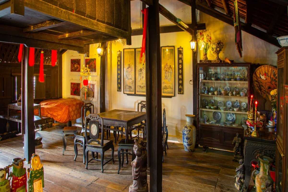 Interior Dining and Worship Room – Phung Hung Ancient House Traditional wooden interior of Phung Hung Ancient House in Hoi An showing antique dining table, ancestral altar, and cultural relics.