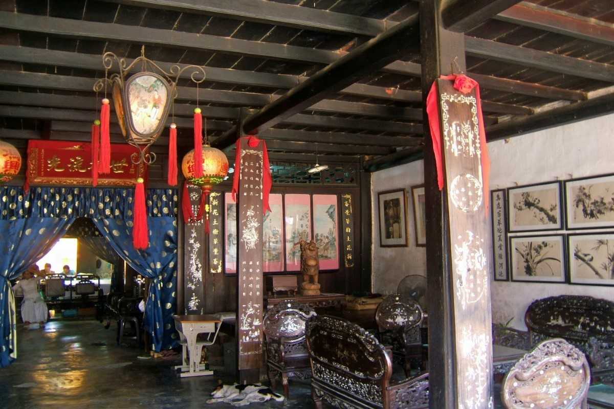 Traditional Living Space – Phung Hung Ancient House Historic sitting room in Phung Hung Ancient House with lacquered wooden furniture, calligraphy, and red hanging lanterns.