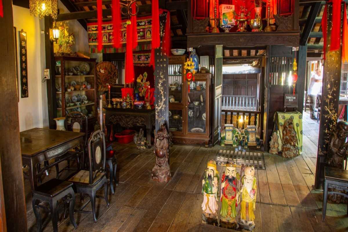 Ancestral Altar and Figurines – Phung Hung Ancient House Ancestral worship space in Phung Hung Ancient House featuring vibrant red lanterns, figurines, wooden altar, and historic artifacts.