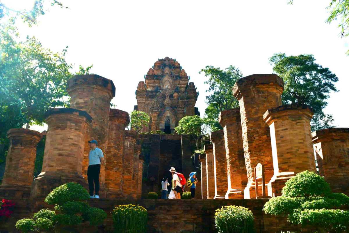 Ancient Cham pillars leading up to Ponagar Cham Towers in Nha Trang surrounded by greenery and sunlight