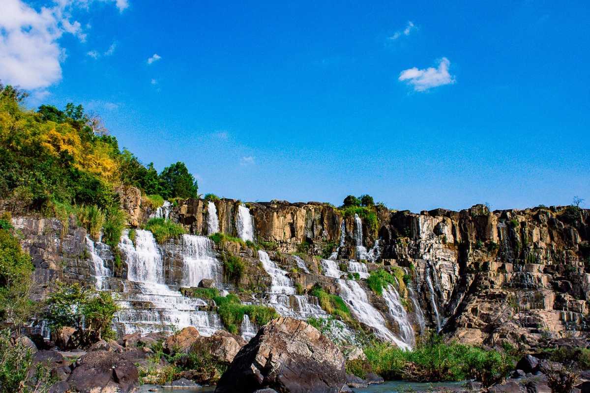 Pongour Waterfalls Dalat bright sunny day waterfall view Bright sunny day highlights the sparkling waters cascading over the rugged terrain at Pongour Waterfalls Dalat.