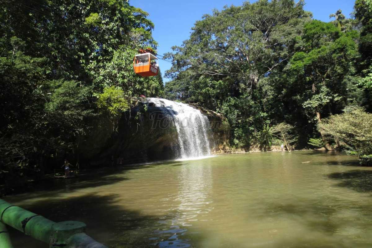 Prenn Waterfall Da Lat cable car over calm waters Prenn Waterfall Da Lat with a red cable car traveling above calm, green waters surrounded by dense forest greenery.