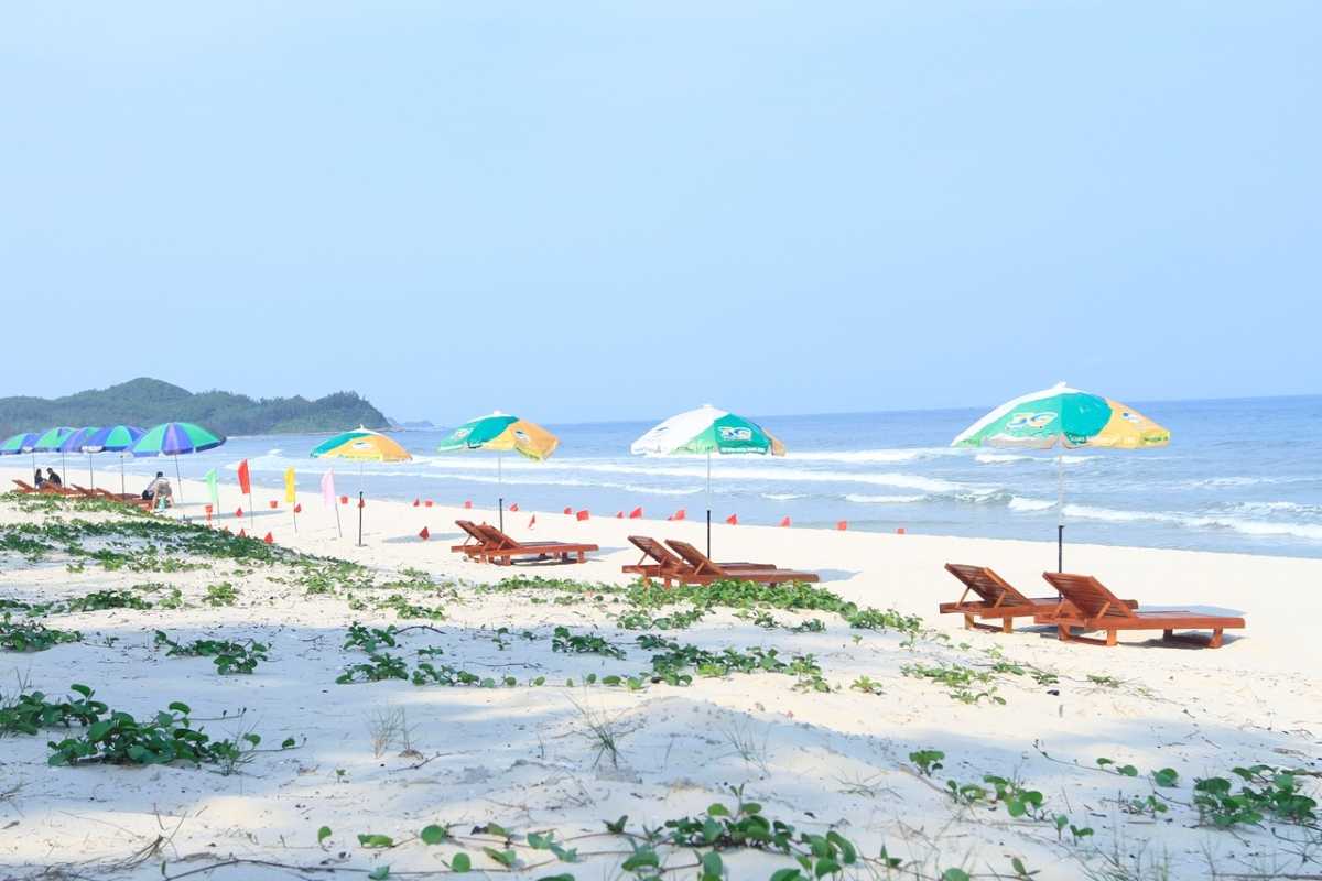 Quan Lan Island pristine beach with sun loungers and umbrellas Quan Lan Island beach with white sand, colorful umbrellas, and wooden loungers along the peaceful shoreline