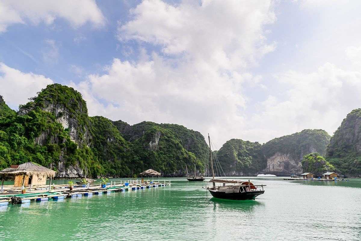 Speedboats docked at Quan Lan Island pier Several speedboats docked at Quan Lan Island pier with clear blue waters and green hills in the background