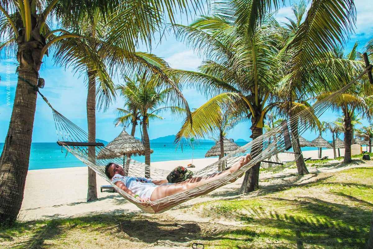 Relaxing Hammock on An Bang Beach Person resting on a hammock tied between palm trees on the sandy beach