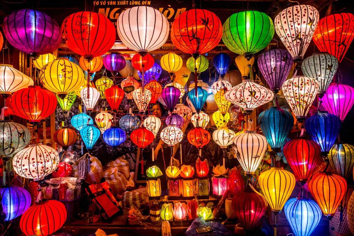 Riverside Food Stall at Night in Hoi An Night Market Riverside food stall with a sign advertising traditional dishes, glowing under lantern light at Hoi An Night Market