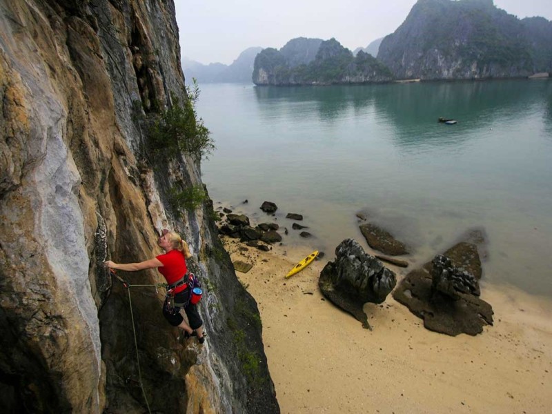 Climber scaling a rock face on Tiger Beach, Cat Ba Island