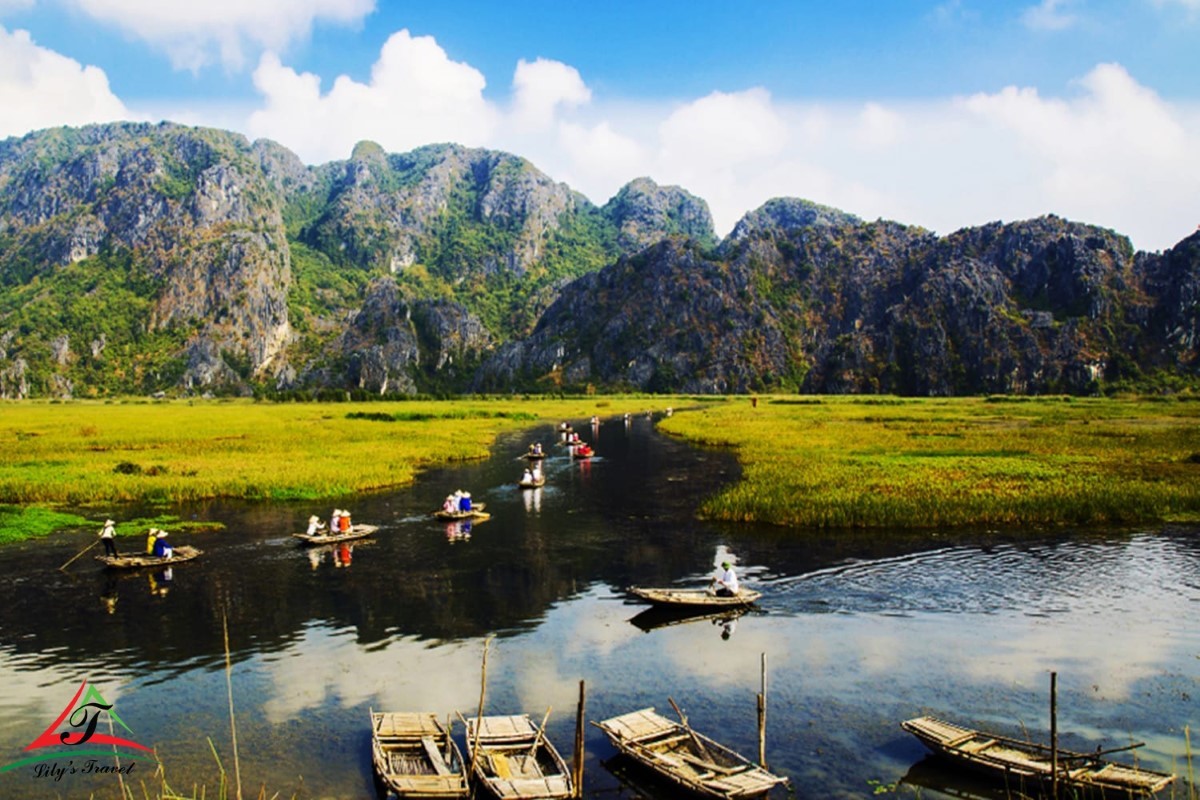 People sailing in Van Long Lagoon surrounded by limestone mountains, showcasing the natural beauty of Van Long Nature Reserve.