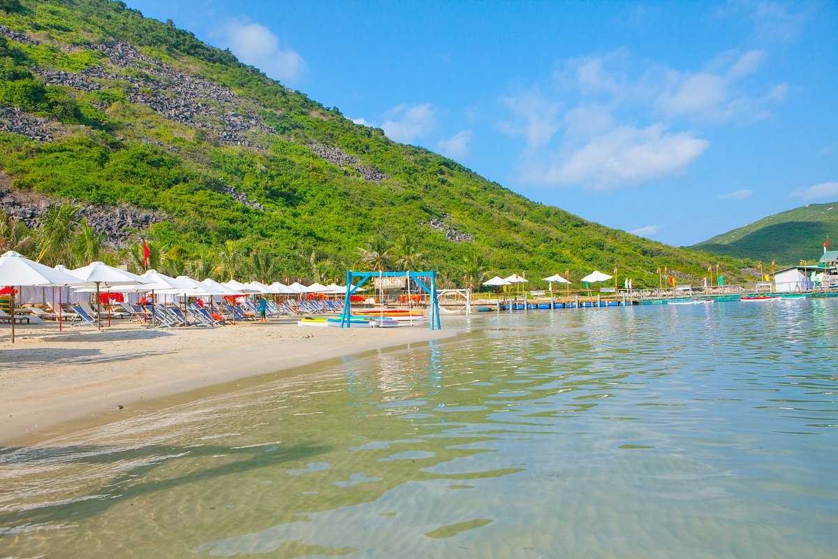 Sandy Shoreline and Clear Waters at Robinson Beach Nha Trang Soft sandy shoreline meeting clear blue waters with beach chairs and umbrellas at Robinson Beach Nha Trang