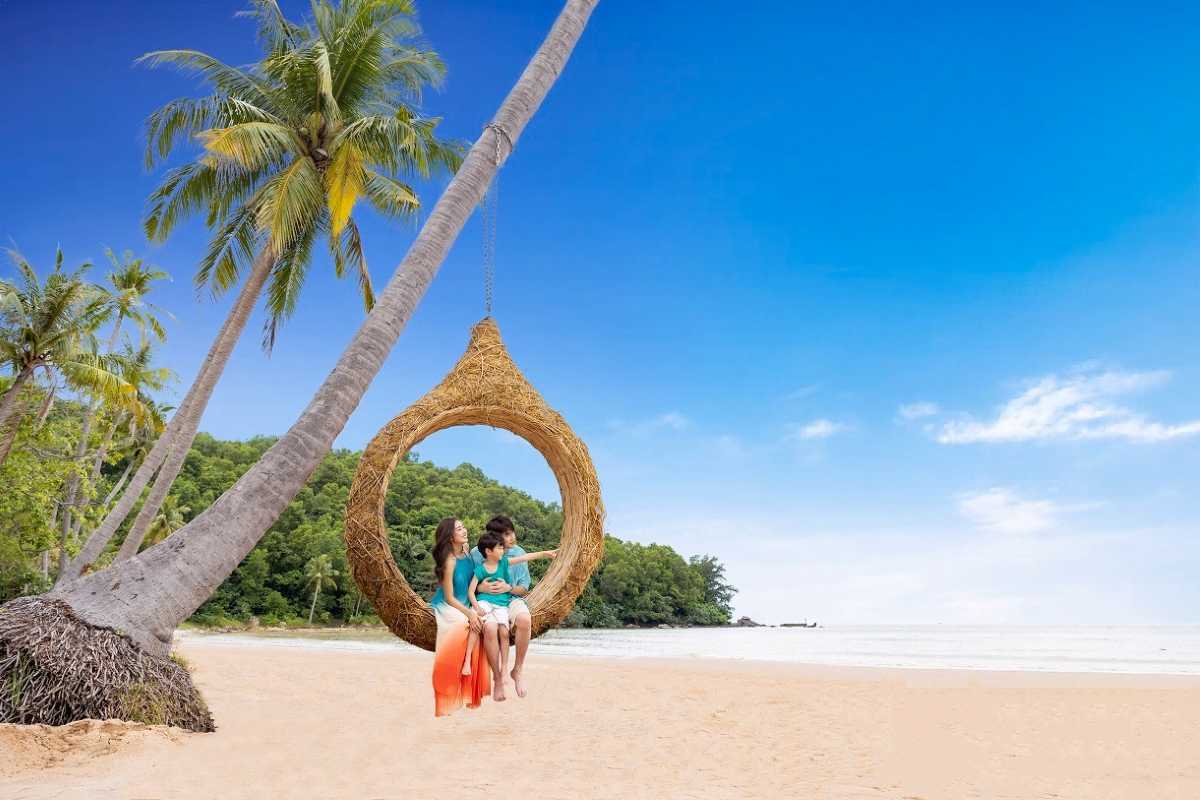 Family Enjoying Beach Swing at Sao Beach Phu Quoc Family sitting on a wooden beach swing under coconut palms at Sao Beach Phu Quoc