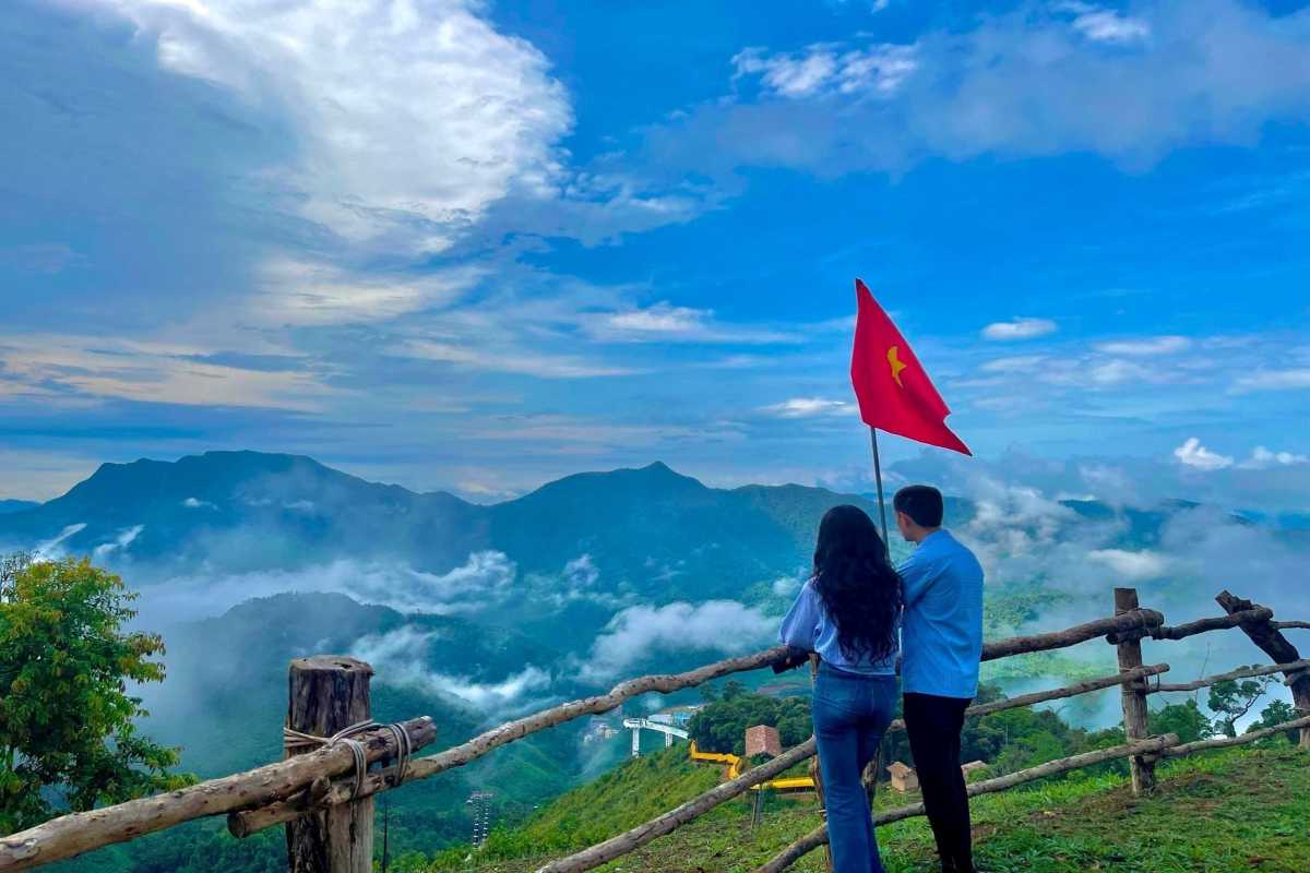 Sapa Heaven Gate Vietnam couple flag panoramic view Couple with Vietnam flag at Sapa Heaven Gate looking over foggy mountains and lush green valleys
