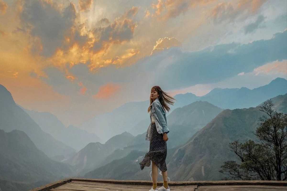 Sapa Heaven Gate golden hour mountain boardwalk experience Woman on Sapa Heaven Gate wooden boardwalk during golden hour with colorful sky and mountain silhouettes