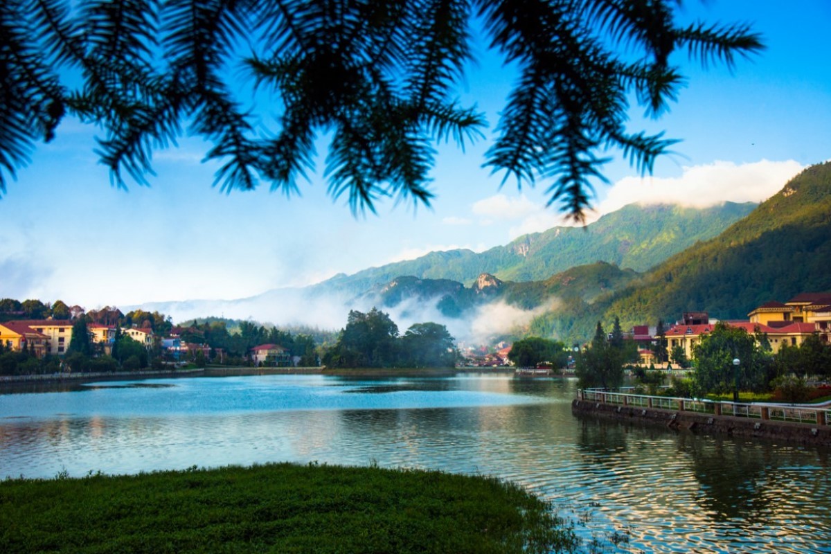 Sapa Lake in Northern Vietnam with mountain backdrop and willow branches framing the scene.