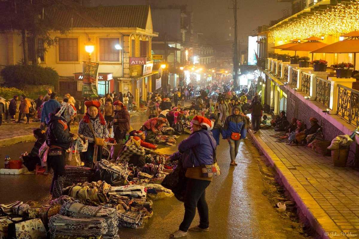 Sapa Love Market bustling evening with traditional crafts on main street Sapa Love Market’s main street is filled with locals selling handmade crafts and textiles under warm evening lights in Sapa.