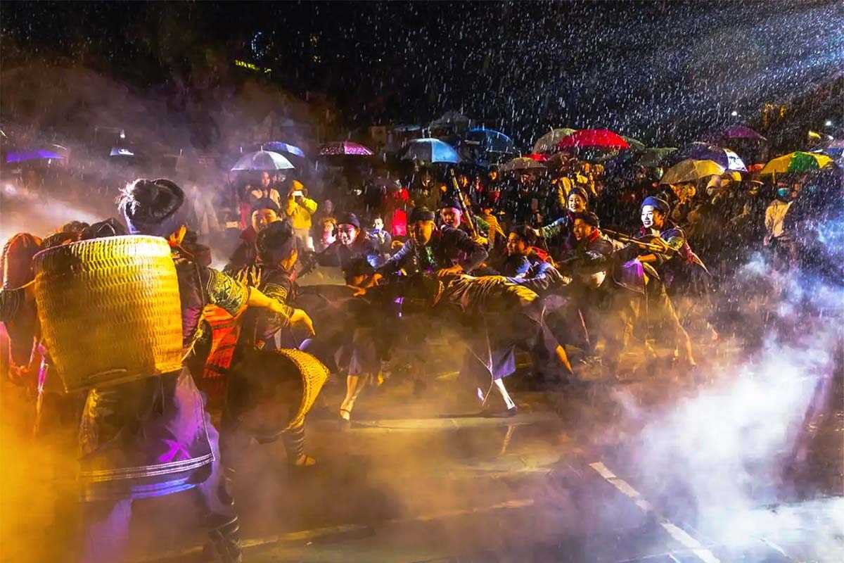 Sapa Love Market rainy night with cultural performances Sapa Love Market in Sapa, Vietnam showcases locals performing in traditional dress during a rainy evening, surrounded by mist.