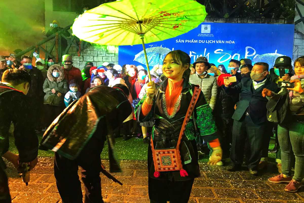 Sapa Love Market Vietnam umbrella parade at night Sapa Love Market Vietnam parade features a girl in ethnic costume with a bright umbrella amid a festive night crowd.