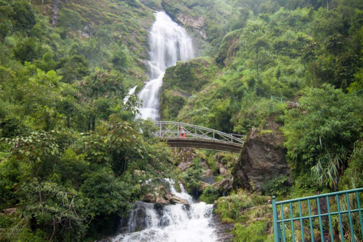 Sapa Love Waterfall bridge scenic crossing Sapa Love Waterfall with a metal bridge spanning the stream, surrounded by lush forest and flowing water