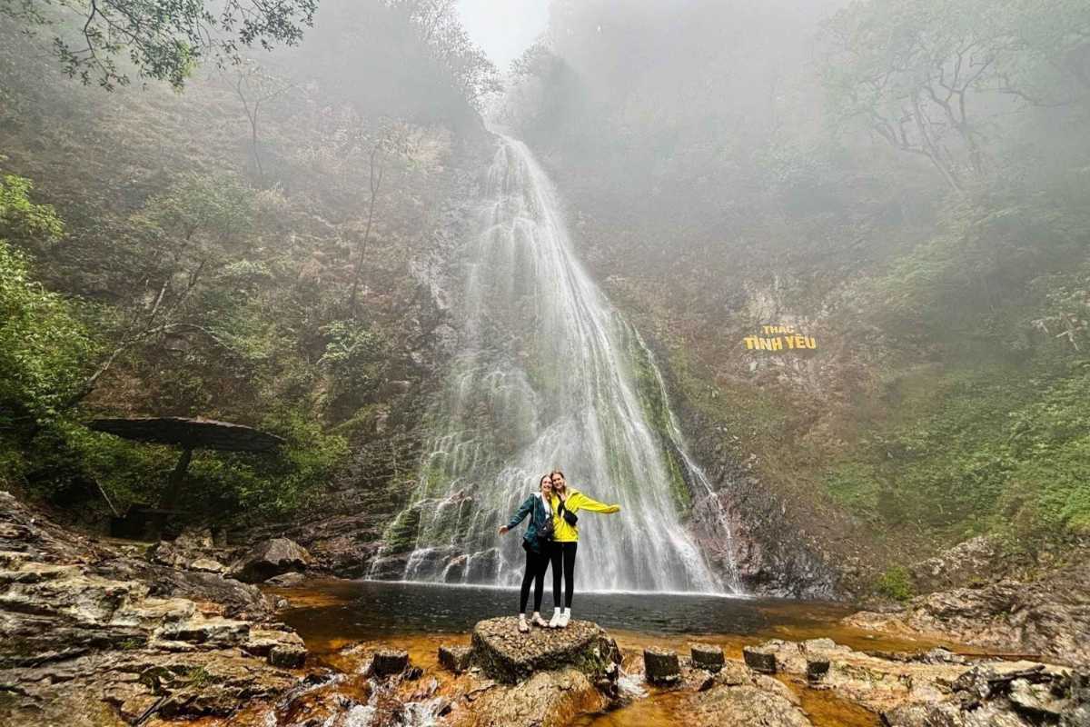 Sapa Love Waterfall foggy morning romantic shot Two visitors stand arm in arm at the base of Sapa Love Waterfall, surrounded by mist and a foggy forest