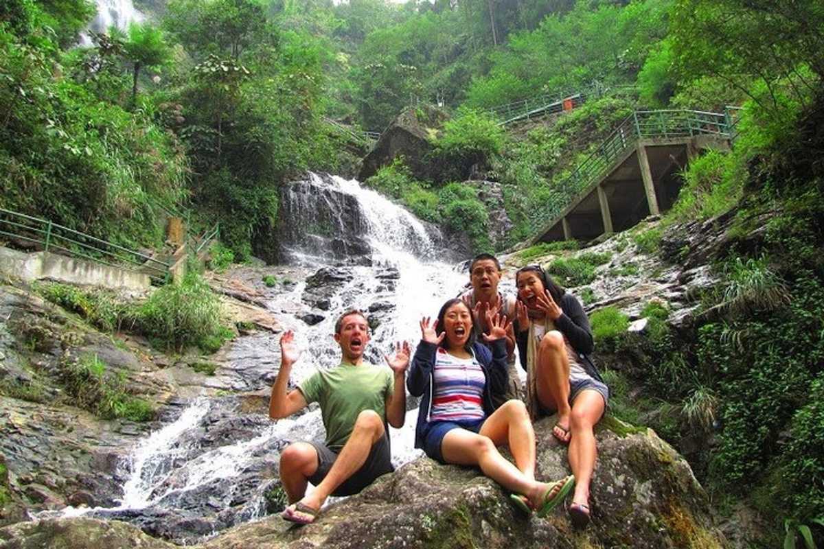 Sapa Love Waterfall fun by rocky stream Four travelers enjoy laughter and fun while sitting on rocks by the lively waters of Sapa Love Waterfall’s lower stream