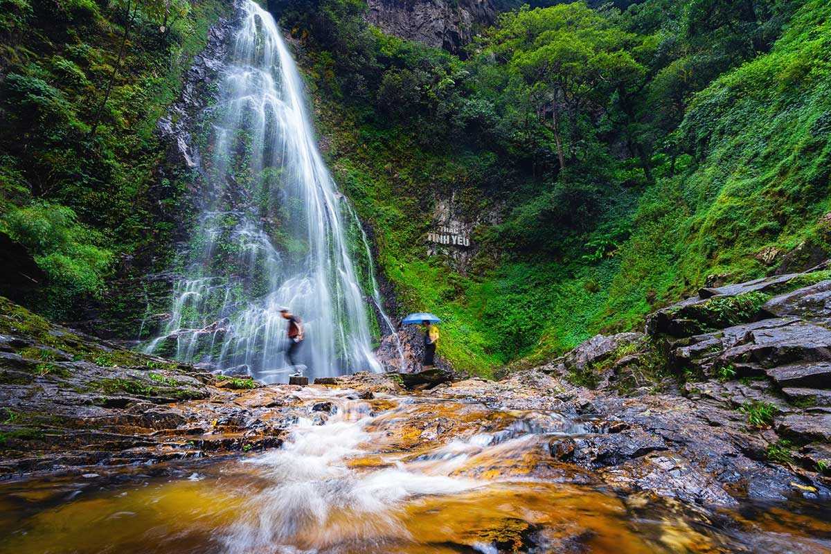 Sapa Love Waterfall main cascade long exposure Sapa Love Waterfall’s main cascade flows gracefully into a pool, captured in a long-exposure shot with visitors nearby