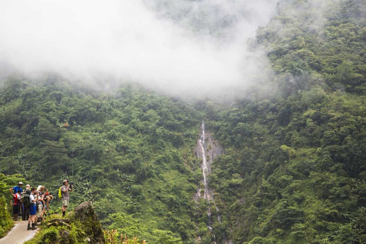Sapa Love Waterfall Vietnam mountain view with hikers Sapa Love Waterfall seen through lush mountains and mist, with a group of hikers taking photos on a scenic trail